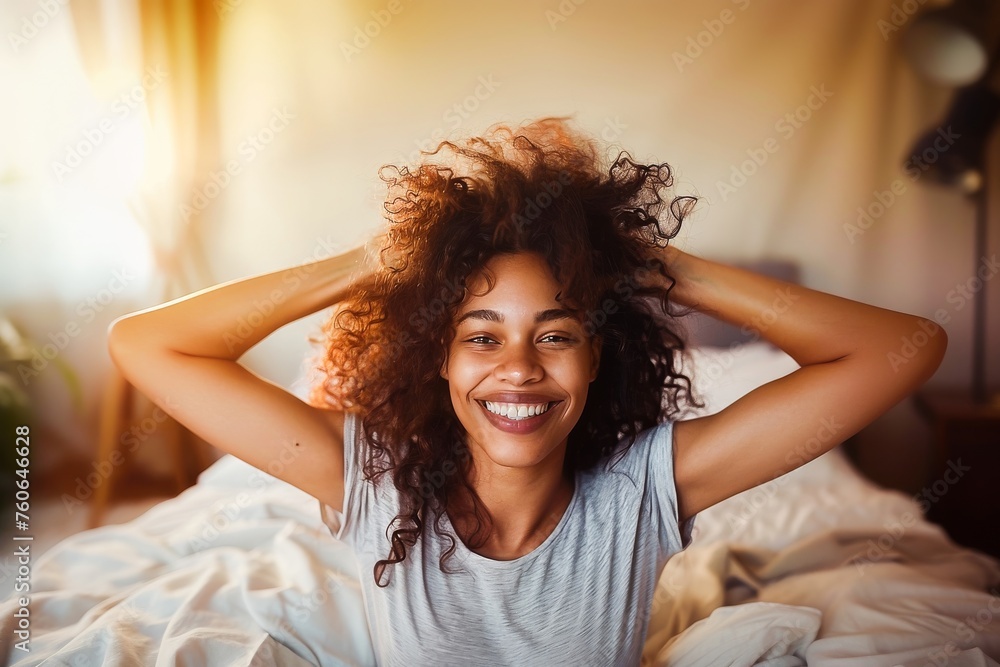 A joyful young woman with curly hair smiling brightly in a sunny bedroom, exuding happiness and comfort. A joyful young woman with curly hair smiling brightly in a sunny bedroom, exuding happiness and comfort.
