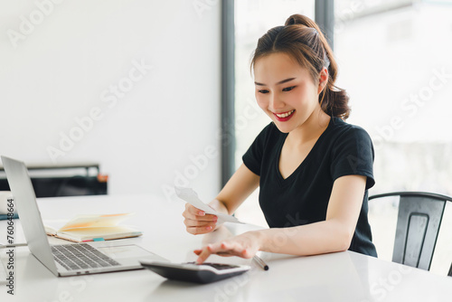 Happy Asian Businesswoman Calculating Finances on Desk.