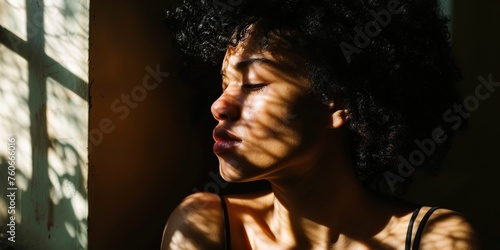 A person sitting by a window with a soft light casting thoughtful shadows on their face , concept of Contemplation