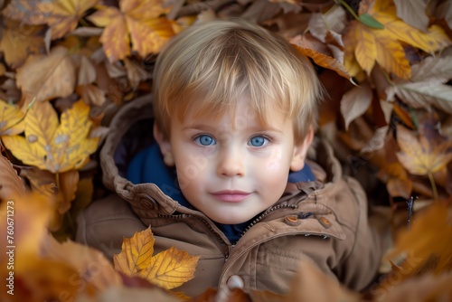 Boy covered in autumn leaves smiling
