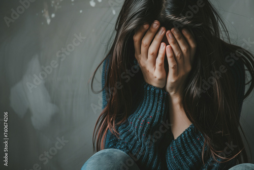 woman sitting with their face buried in their hands, which can be indicative of sadness, grief, or despair.