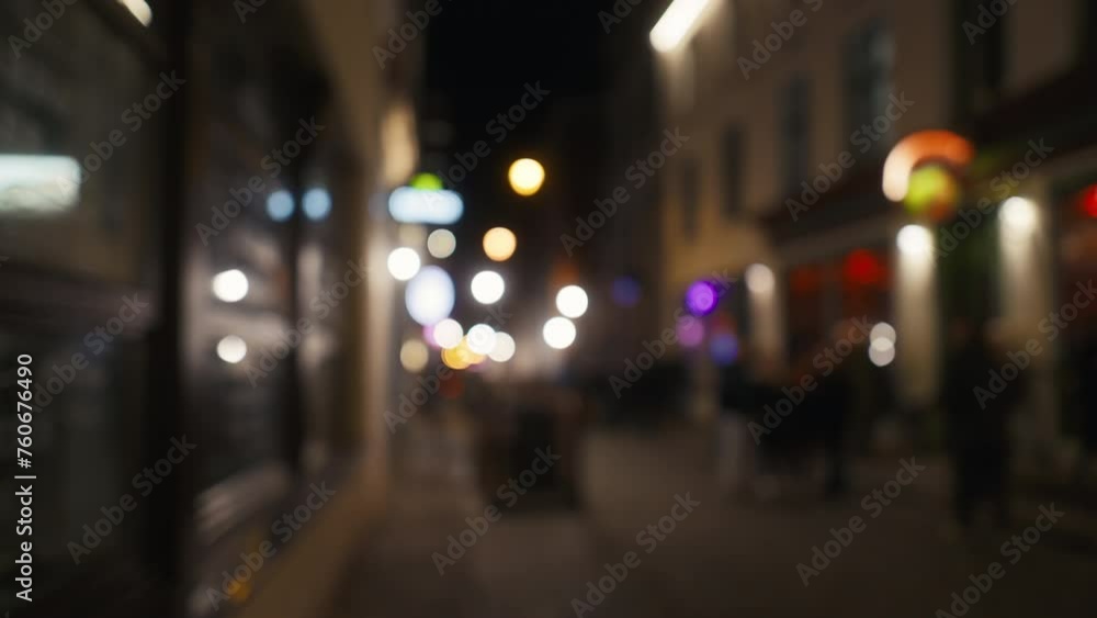 Blurred city street at midnight with people walking under electric blue fixtures Blurred city street at midnight with people walking under electric blue fixtures