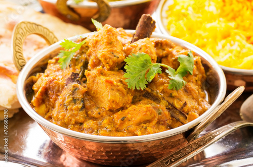 Traditional Indian chicken curry served with spices and chicken pieces as close-up in a kadai bowl photo