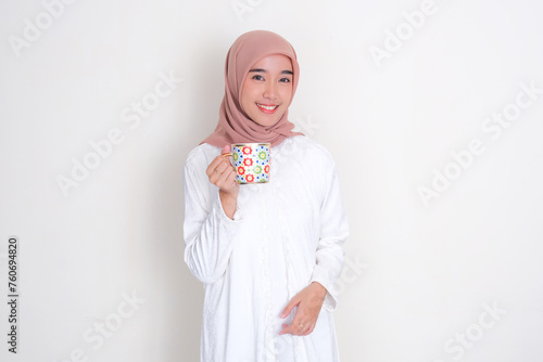 Moslem Asian woman smiling at the camera while holding a drinking glass photo