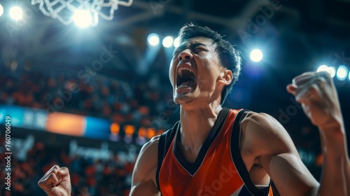 Asian basketball player celebrates victory, unleashing shouts of joy against the backdrop of a basketball stadium. Emotional celebration of winning the game photo