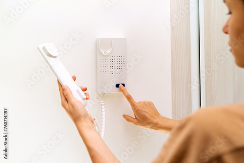 Using intercom at home. Woman uses intercommunication device at her apartment. Using intercom at home.