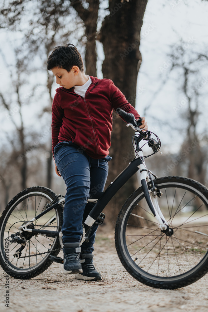 A boy takes a relaxing bike ride along a park trail, experiencing the joy and freedom of childhood outdoors. A boy takes a relaxing bike ride along a park trail, experiencing the joy and freedom of childhood outdoors.