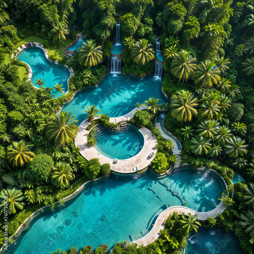 A drone shot of a luxury swimming pool in the jungle, jungle trees, waterfalls, luxury mansion and garden, blue water, summer paradise, summer vacation, travel inspiration, tropical island, holiday