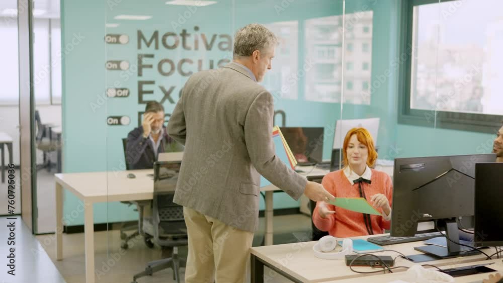 Boss delivering work folders to his employees in a office Boss delivering work folders to his employees in a office
