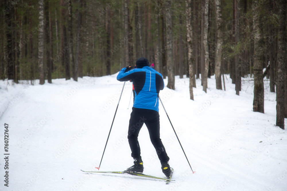 People ski in winter on a ski track through a winter forest.Cross Country skiing. People ski in winter on a ski track through a winter forest.Cross Country skiing.