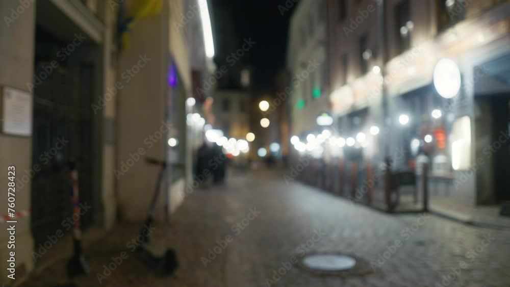 Blurred video of city street at night with fence, lights, and building facade Blurred video of city street at night with fence, lights, and building facade
