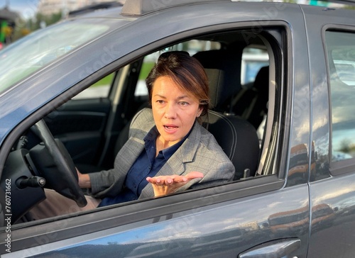 Close up of Caucasian pretty woman sitting in auto looking through window with pretentious face expression. Traffic. Woman driver unhappy with road trip. Trip concept © Nataliya