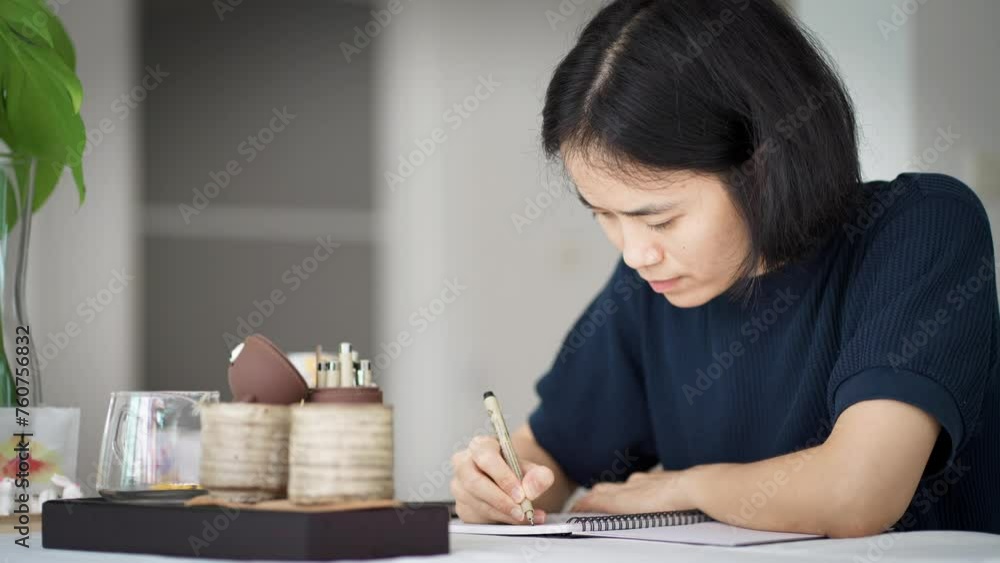 Woman writing down her thoughts on notebook at home, work space concept.

