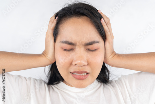 A woman with her head down and her hands on her ears.