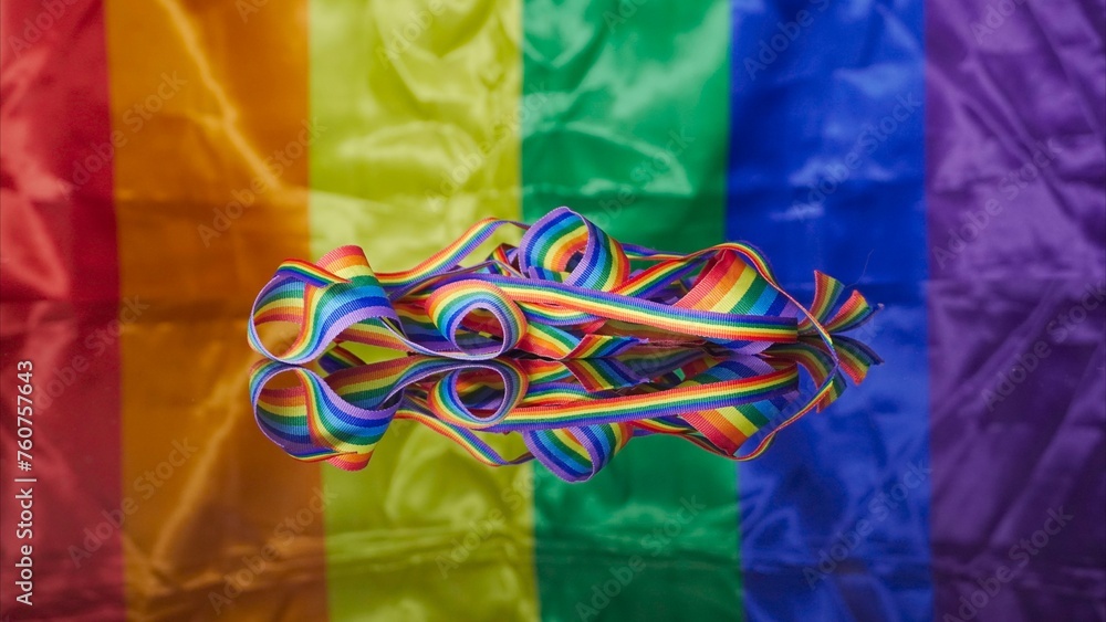 Some rainbow colored ribbons on the reflective surface and LGBT flag on the background