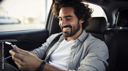 Man smiling joyfully while looking at his phone in his car.