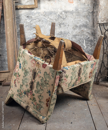 Defective old broken armchair in an old dirty room with other vintage things
