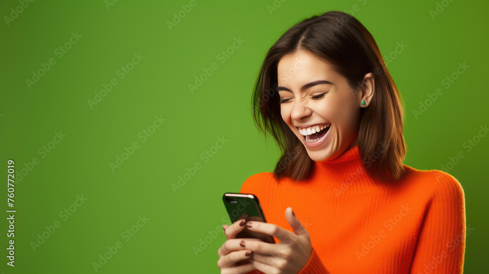 Happy smiling young woman is using her smartphone against green background Happy smiling young woman is using her smartphone against green background