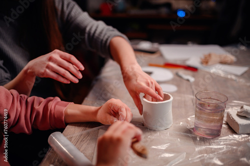 Close-up of hands carefully molding clay, capturing the essence of tactile learning and artistic expression during a family crafting session