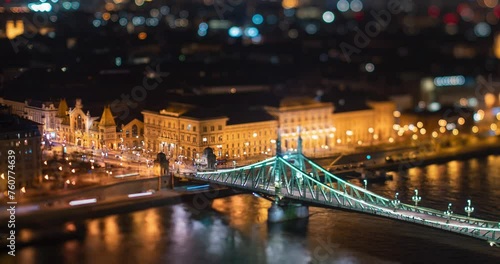 Budapest, Hungary - February 7, 2024: Landscape view of night Budapest from Citadella observation deck. Focus tilted to Fovam Ter street. Liberty bridge and Central Market on the middleground. photo