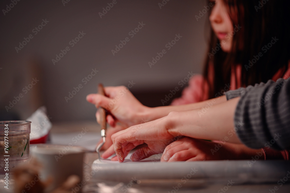 A mother and daughter's hands work in harmony during a home crafting workshop, emphasizing the tactile joy of art and the shared experience of making A mother and daughter's hands work in harmony during a home crafting workshop, emphasizing the tactile joy of art and the shared experience of making