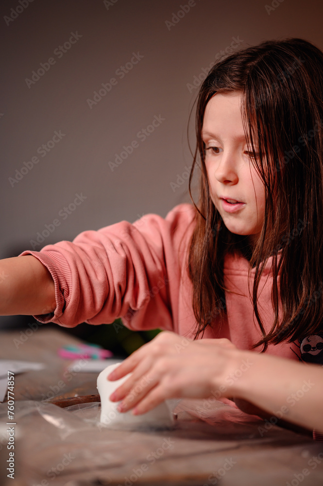 A young girl concentrates deeply on molding clay, her hands dusted with flour, in a vibrant example of youthful creativity and the joy of hands-on art A young girl concentrates deeply on molding clay, her hands dusted with flour, in a vibrant example of youthful creativity and the joy of hands-on art