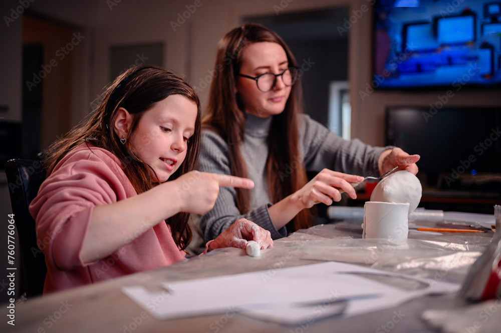 The sheer delight of a girl sculpting with clay is shared with her mother, capturing the essence of joyous learning and creative expression within the family The sheer delight of a girl sculpting with clay is shared with her mother, capturing the essence of joyous learning and creative expression within the family