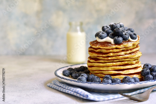 Stack of fresh hot pancakes with maple syrup and blueberries.