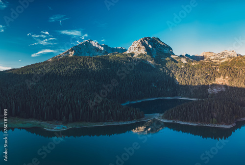 Drone shot of lake with lots of forest and mountain peaks in background, early in the morning, during autumn, Black Lake, Durmitor, Montenegro photo