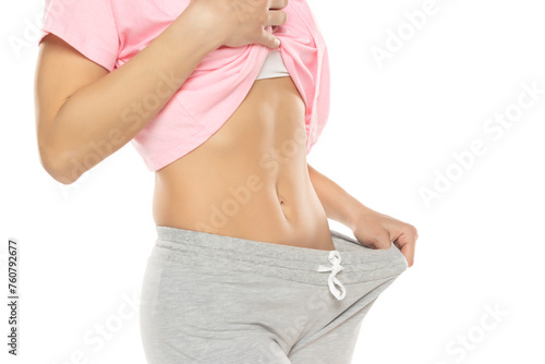 Fit woman showing flat belly on a white background. Closeup.