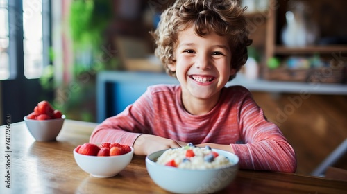 Happy boy sitting at a table with a plate of fruit having a meal at home. Young boy in casual clothes preparing to eat fruit while smiling and looking at the camera. Cheerful boy getting ready to eat.
