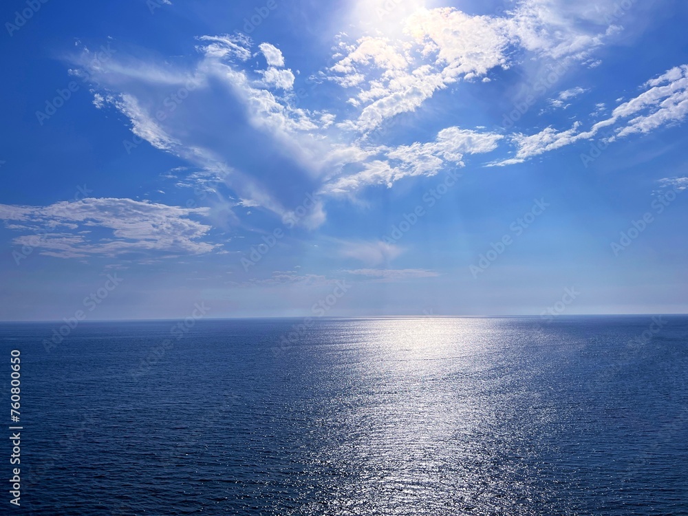 Blue glittering sea and sky clouds 