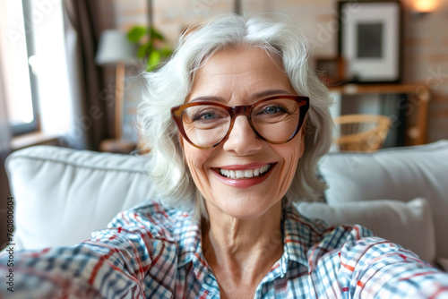 Technology, communication and people concept - happy smiling senior woman in glasses taking selfie at home