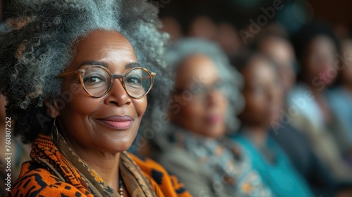 Portrait of a stylish senior African American woman with gray hair, smiling confidently in a blurred background.
