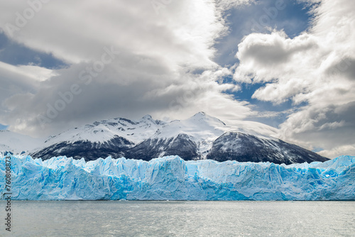 Paisagem do glaciar Perito moreno, com sua majetosa parede de gelo azul e ao fundo montanhas nevadas em dia com nuvens photo