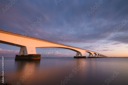 Zeeland bridge, Netherlands. A long bridge over the sea during sunset. Long exposure photo. Landscape during a bright sundown. The sea and the bridge.