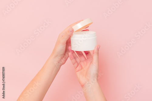 Round jar of cosmetic cream in hand on pink background. Cosmetics beauty mockup for product branding