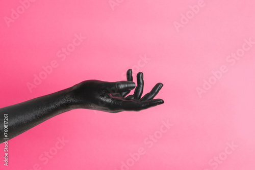 Black painted elegant woman's hand on her skin gesticulates on pink background. High Fashion art concept photo