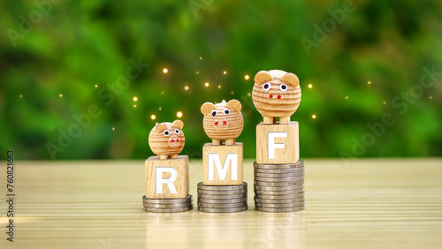 Rows of money coins stacks with RMF word and piggy bank on wooden cube on nature garden background for Retirement Mutual Fund, planning to retirement and reduce annual tax concept. photo