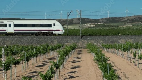 TREN DE VIAJEROS POR EL CAMPO, FONDO CON MOLINOS EOLICOS photo