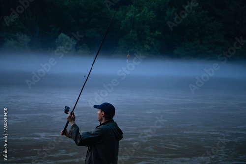Man fishing on the mountain river at evening
