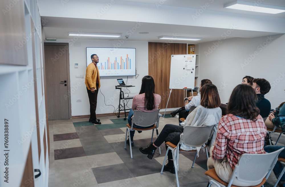 Confident male presenter leads a corporate business meeting, delivering an engaging presentation to attentive colleagues in a modern office setting.