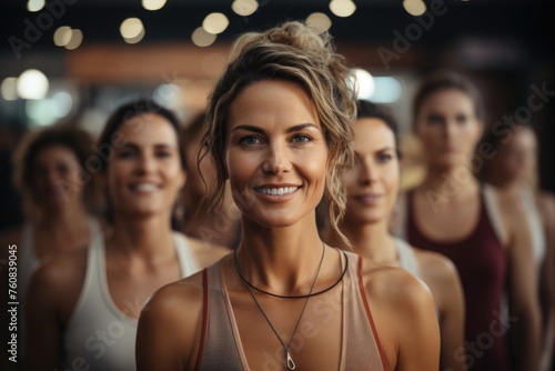 Group of smiling young women in sportswear looking at camera in gym