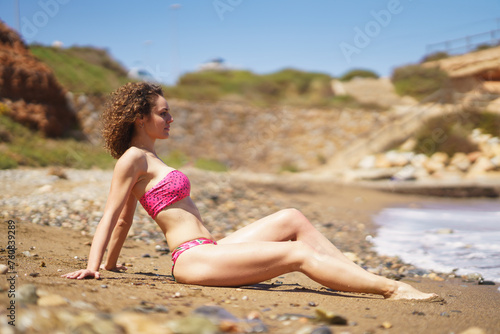 Slim woman in bikini sitting on beach