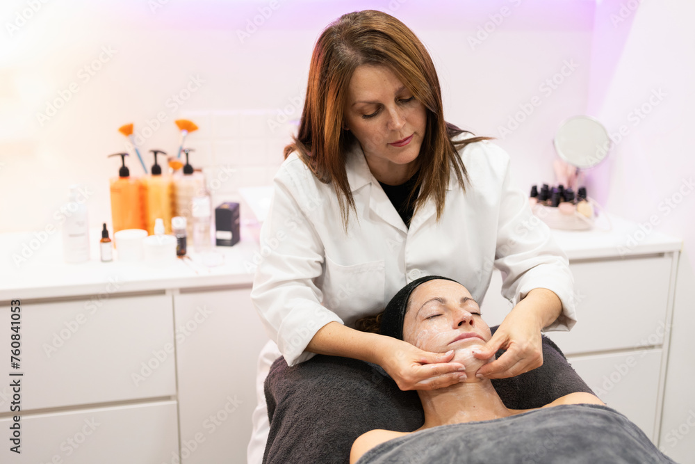 Beautician massaging face of female customer in beauty salon Beautician massaging face of female customer in beauty salon