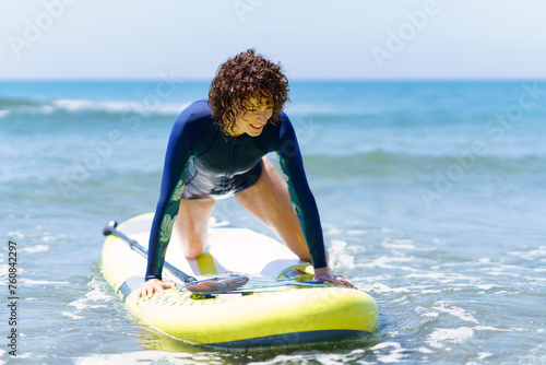 Young female surfer with SUP board in sea