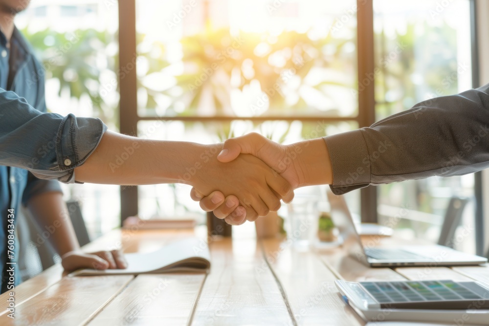 two business people shaking hands together at a conference table two business people shaking hands together at a conference table