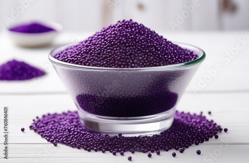 Round vessel with purple plastic granules on white table photo
