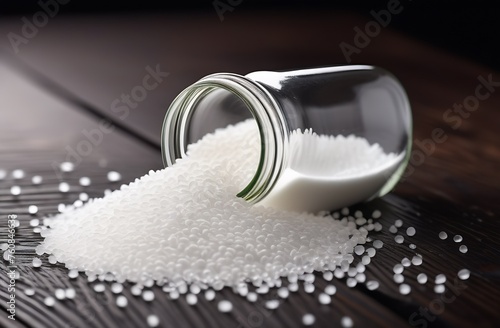 Jar with white plastic granules on wooden table