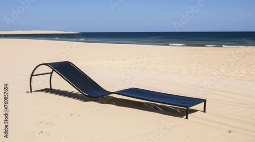 a lounge chair sitting on top of a sandy beach next to a large body of water on a sunny day. photo